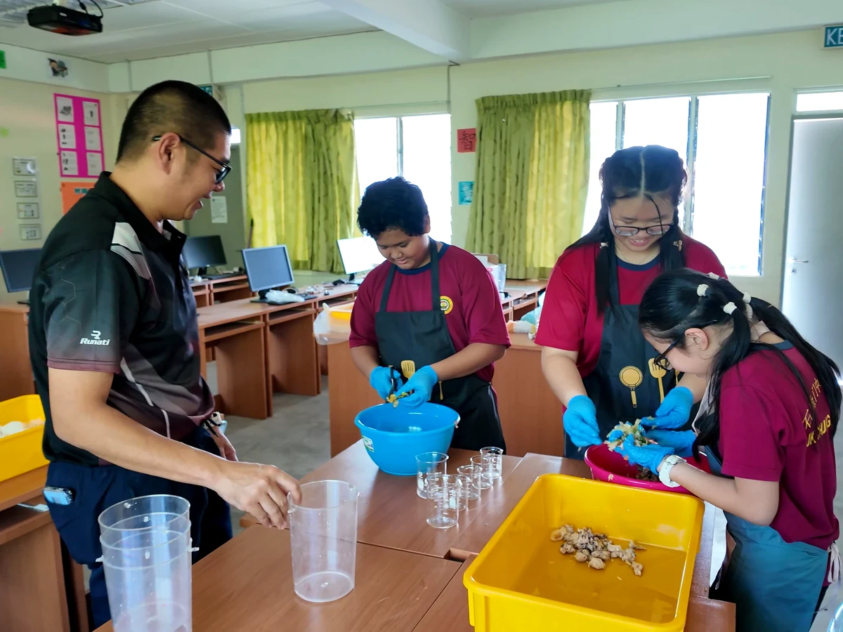 Secondary school students and mentor conducting hands-on laboratory testing with beakers and specimens
