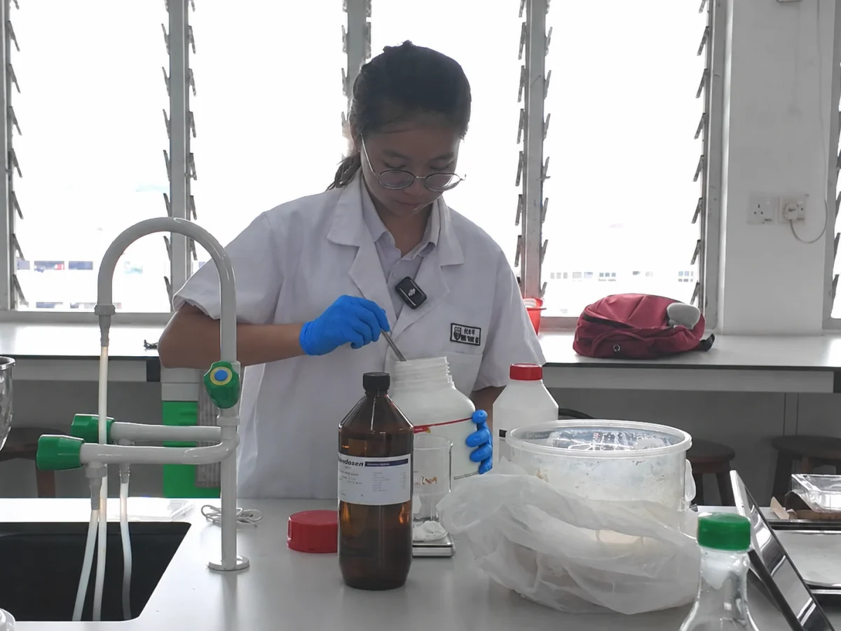 Secondary school student wearing blue nitrile gloves while conducting chemical research in a science laboratory